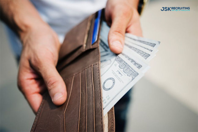 A person holding a wallet with money in it.