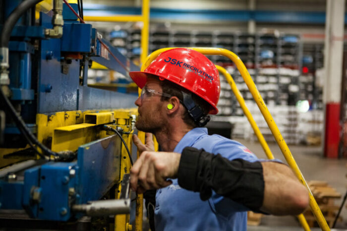 A man in red hard hat working on machine.