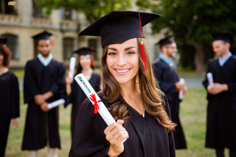 A woman in graduation gown holding her diploma.