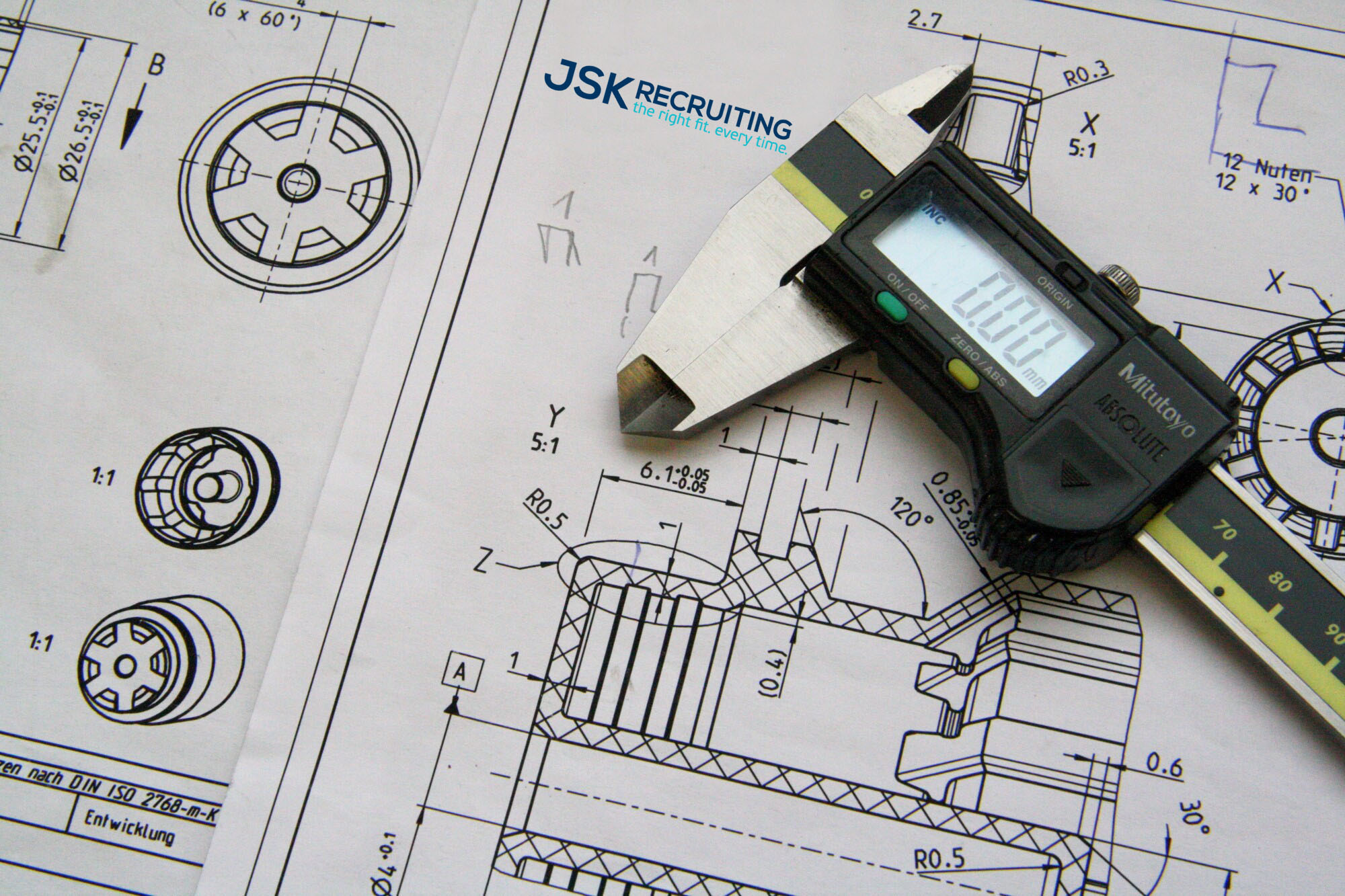 A pair of calipers on top of some blueprints