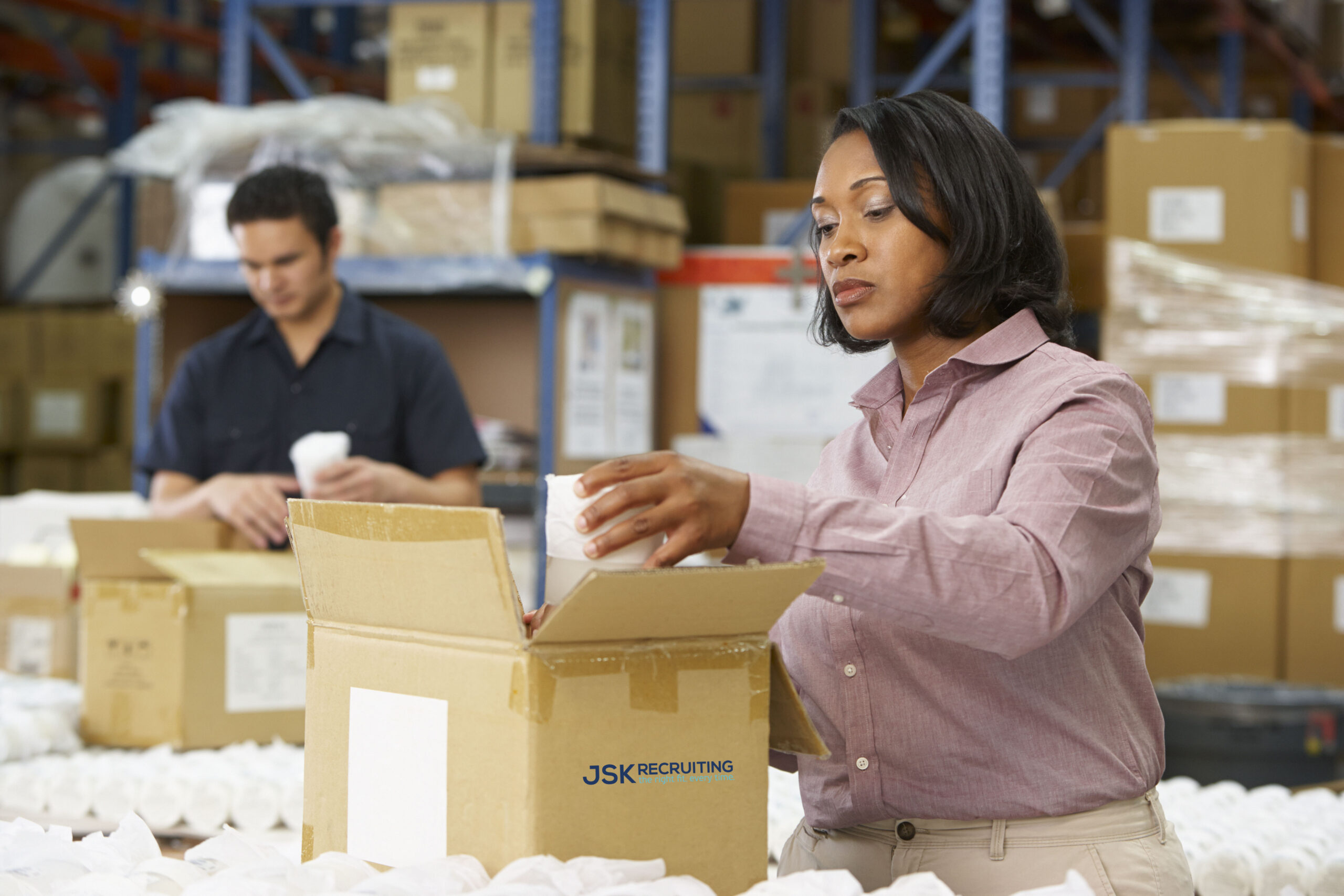 A woman opening up an open box in a warehouse.