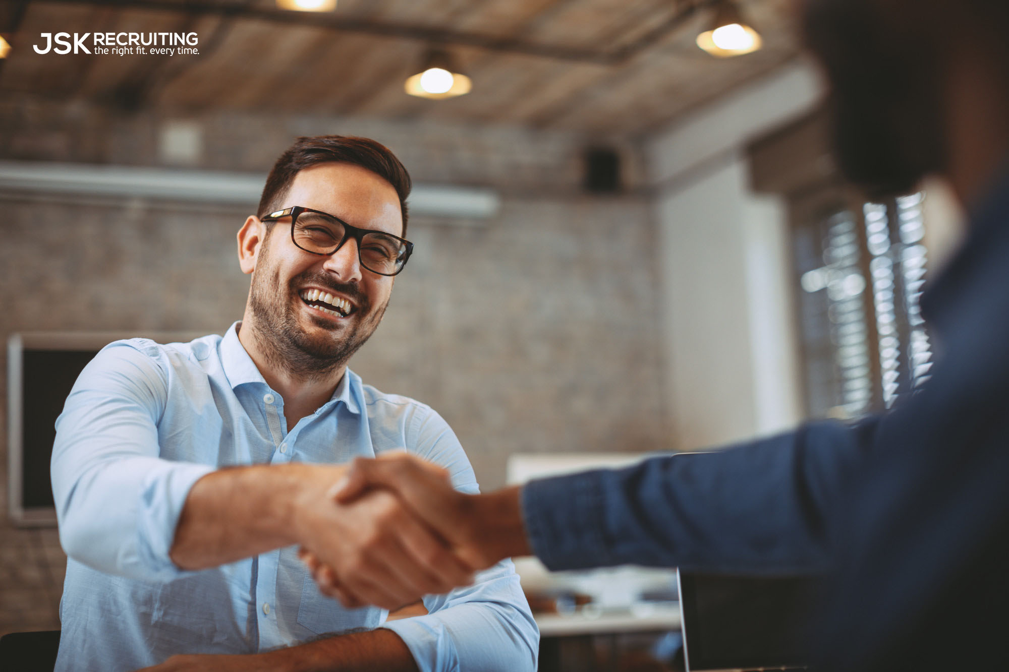 A male recruiter in glasses shakes hands with a client. Photo is watermarked with the JSK Recruiting logo.