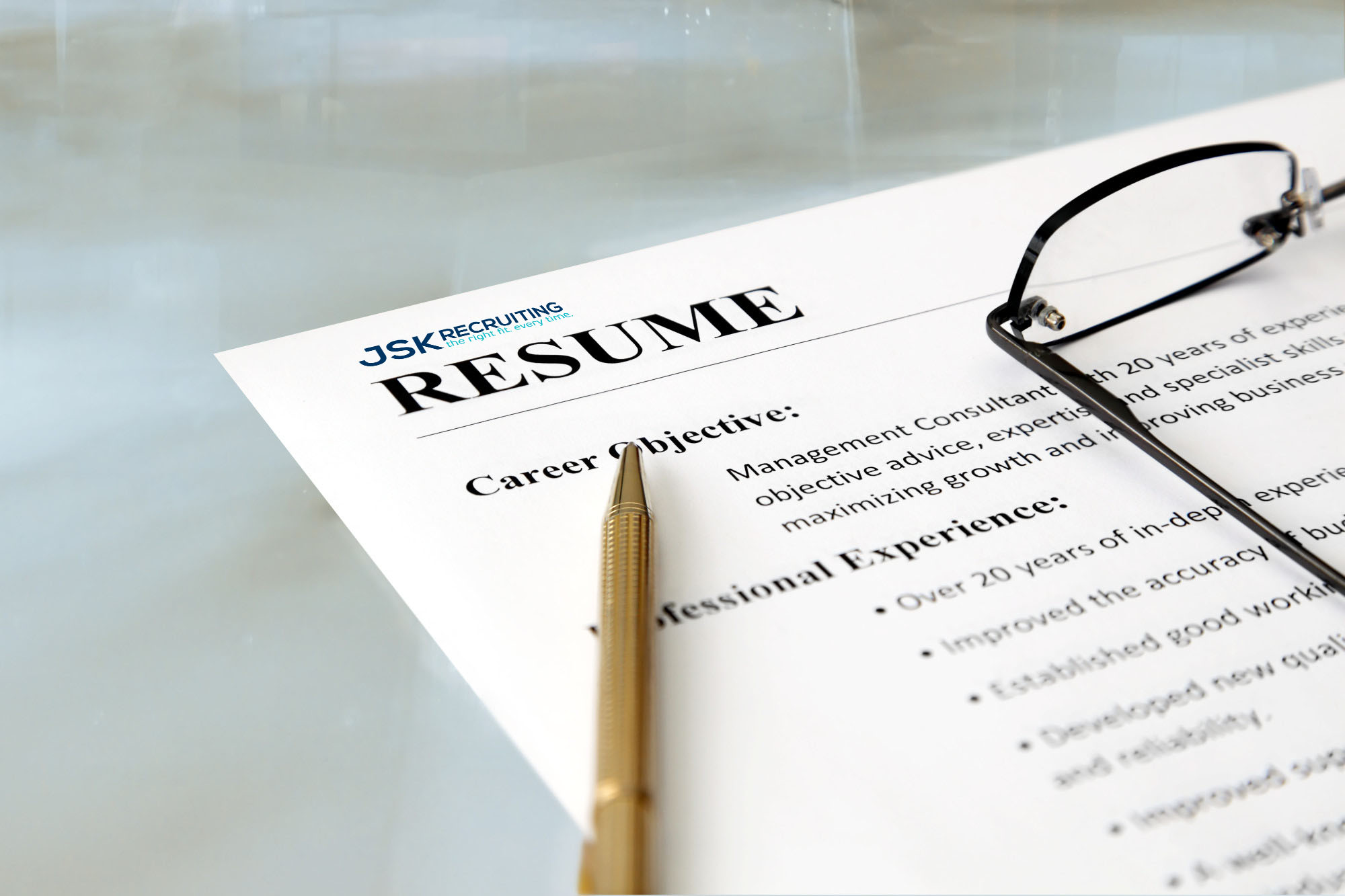 A pencil and some glasses sitting on top of a resume with the JSK Recruiting letterhead.